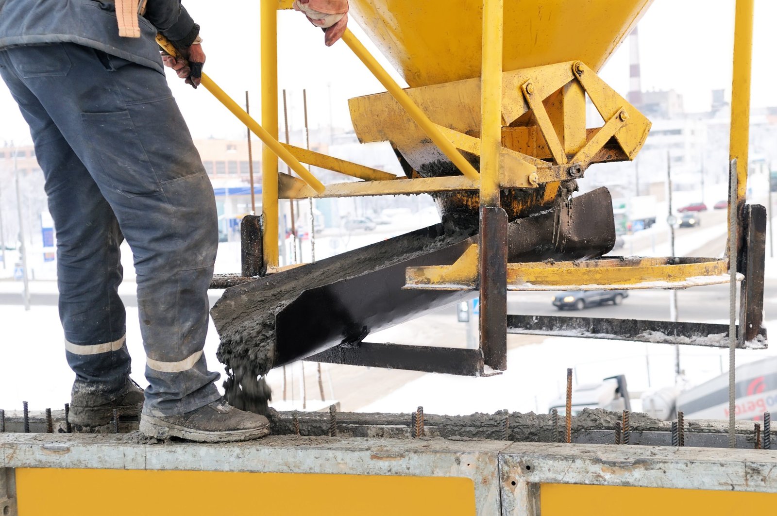 Worker pouring concrete in cold winter weather — low temperatures slow hydration and curing on construction sites