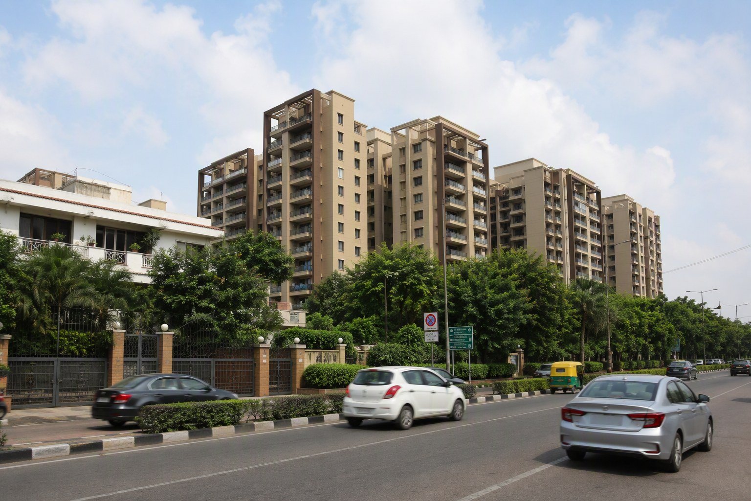 DLF Phase 2 Gurugram street with mid-rise residential apartment towers behind a gated boundary wall